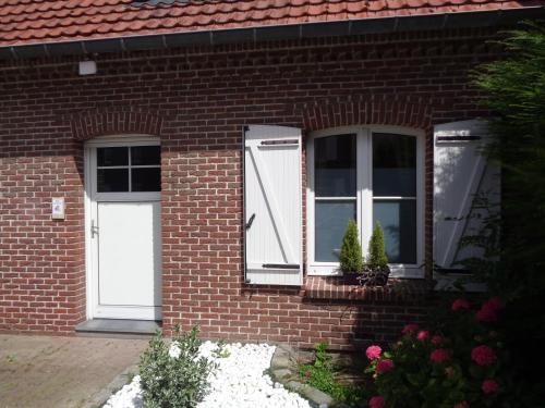 a brick house with a white door and windows at Les Petits Souliers in Lestrem