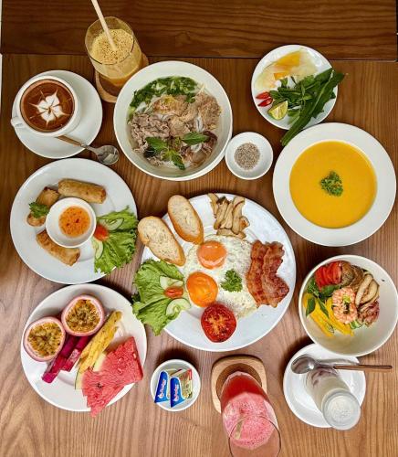 a table with plates of food and bowls of soup at Shoreline Stay in Hoi An
