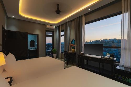 a hotel room with two beds and a desk and a window at Lumina Dalat Premium in Xuan An