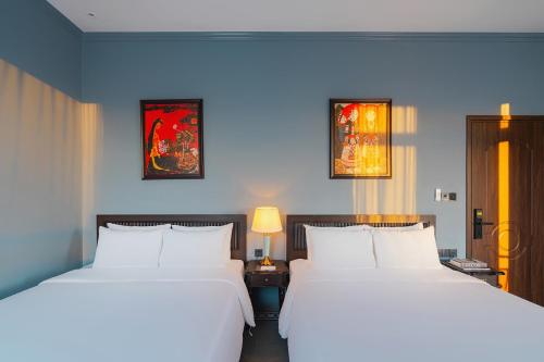 two beds in a room with blue walls at Lumina Dalat Premium in Xuan An