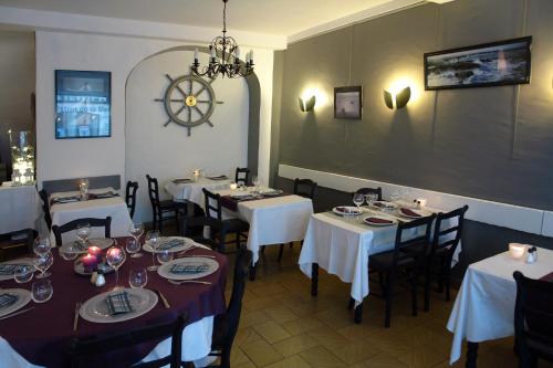 restauracja ze stołami i krzesłami oraz zegarem na ścianie w obiekcie Logis Hôtel Les Chardons Bleus RESTAURANT LE BISTROT DE LA MER w mieście Roscoff