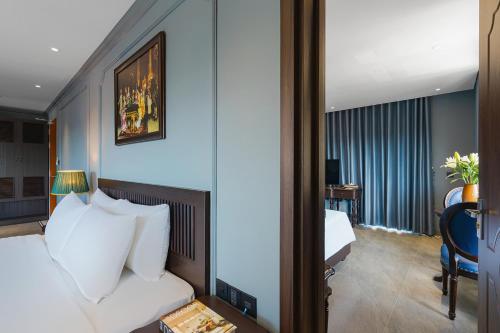 a hotel room with a white bed and a desk at Lumina Dalat Premium in Xuan An