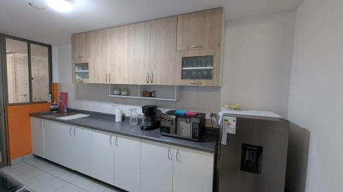 a kitchen with white cabinets and a stainless steel refrigerator at Departamento céntrico con sala comedor y cocina in Pachacutec