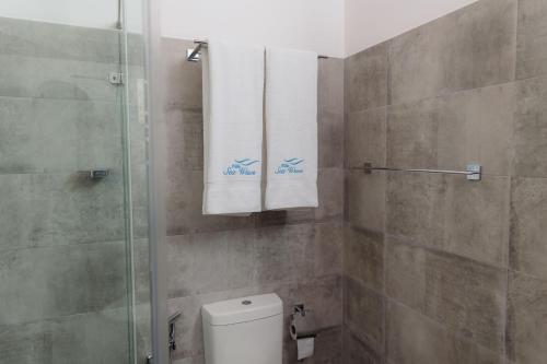 a bathroom with a shower and a toilet and towels at Villa Sea Wave in Hikkaduwa