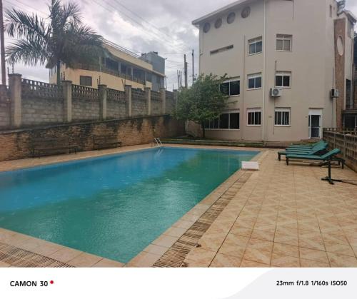 una piscina con un banco junto a un edificio en Green top Cordier apartments, en Kampala