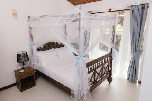 a bedroom with a canopy bed and a window at Villa Sea Wave in Hikkaduwa