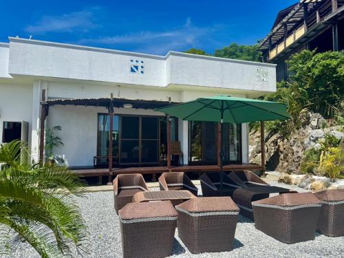 a group of chairs and an umbrella in front of a building at アジアンウッドコテージ in Motobu