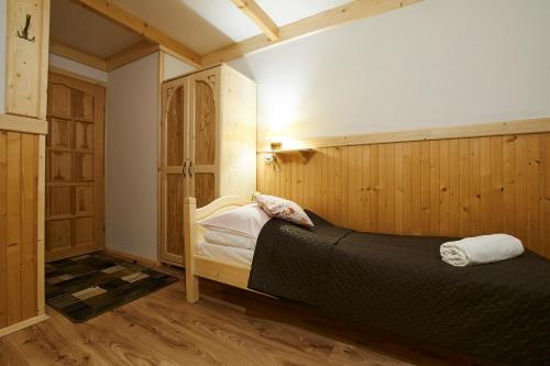 a bedroom with a bed in a room with wooden walls at Noclegi u Hanki in Bukowina Tatrzańska
