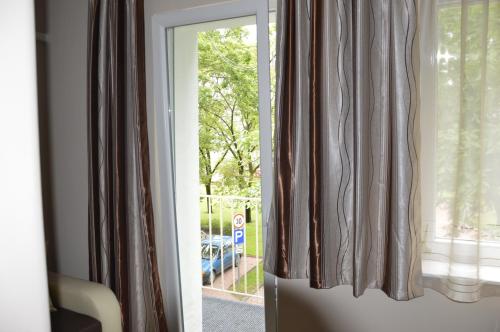 a sliding glass door into a room with curtains at Adél Apartman in Makó