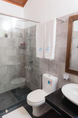 a bathroom with a toilet and a shower and a sink at Villa Sea Wave in Hikkaduwa