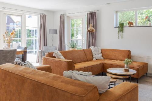 a living room with brown couches and a table at Duinvilla Wetterwille met sauna in Makkum