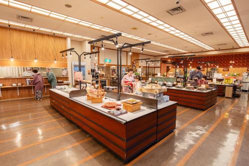 a store with people standing around a food counter at Ooedo Onsen Monogatari Yamanaka Saichoraku in Kaga