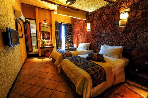 a bedroom with two beds and a stone wall at Hotel Xaluca Dades in Boumalne
