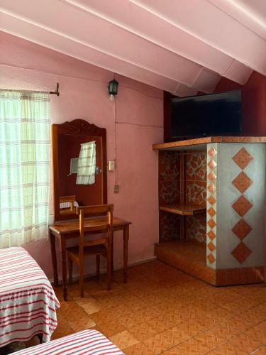 a room with a table and a television and a desk at Hotel Sabrina in Cedro