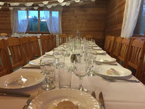 a long table with white plates and wine glasses at Oškrogs in Ķegums