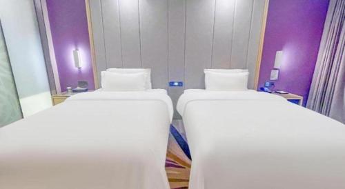 two beds in a room with purple walls at Lavande Hotel Huizhou Shiwan in Huizhou