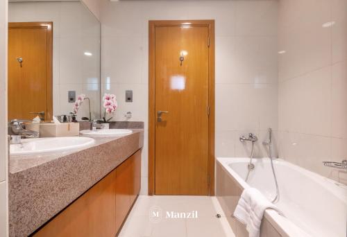 a bathroom with two sinks and a bath tub at Manzil - 4BR Villa in Prime Location with Private Garden in Dubai