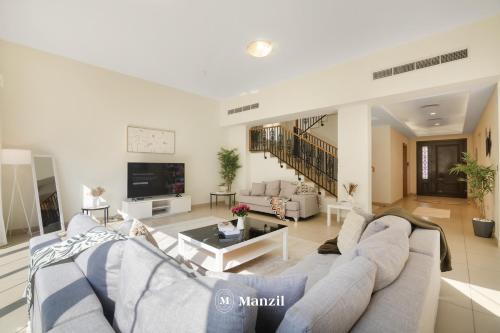a living room with a couch and a table at Manzil - 4BR Villa in Prime Location with Private Garden in Dubai