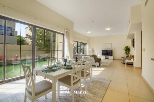 a dining room with a white table and chairs at Manzil - 4BR Villa in Prime Location with Private Garden in Dubai