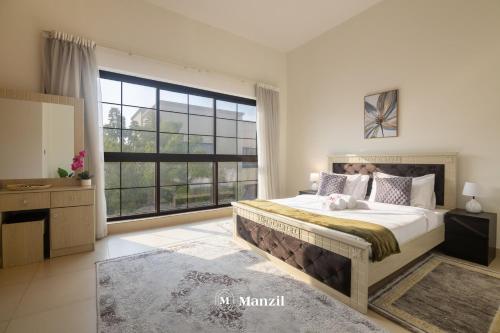 a bedroom with a large bed and a large window at Manzil - 4BR Villa in Prime Location with Private Garden in Dubai