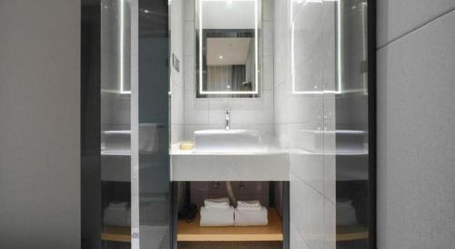 a bathroom with a white sink and a mirror at Green Tree Inn Urumqi San'gong Metro Station Exit in Ürümqi