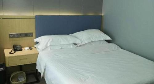 a bedroom with a bed with a blue headboard and a table at Green Tree Inn Urumqi San'gong Metro Station Exit in Ürümqi