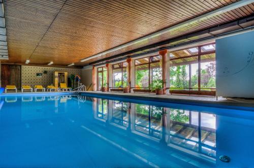 a swimming pool with blue water and windows at WAGNERS Hotel im Fichtelgebirge in Warmensteinach