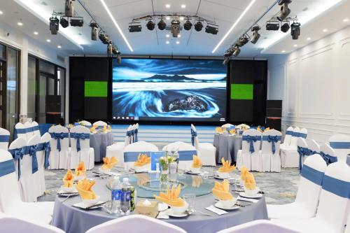 a conference room with tables and chairs and a projection screen at INDOTEL HALONG HOTEL in Ha Long