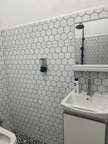 a bathroom with white tiled walls and a sink at Villa Cempaka Homestay in Changlun