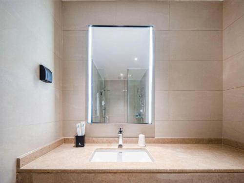 une salle de bain avec un lavabo et un miroir dans l'établissement City Comfort Inn Nanning Puluowangsi, à Nanning