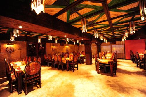 a dining room with wooden tables and chairs and chandeliers at Hotel Xaluca Dades in Boumalne