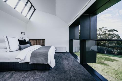 a bedroom with a large bed and a large window at Alkina Lodge Yulu in Wattle Hill