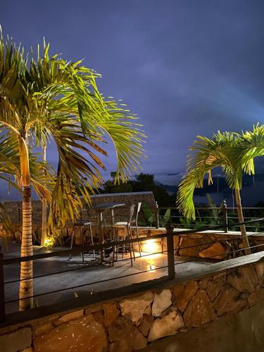 a patio with a table and palm trees at night at Monte Ixk'al in Xilitla