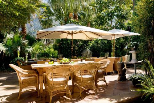 a wooden table with chairs and an umbrella at Hotel Can Roses in Sóller