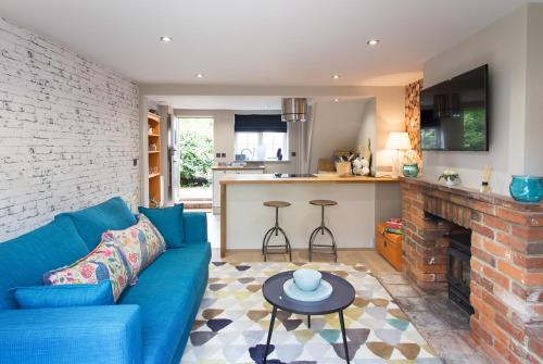 a living room with a blue couch and a fireplace at No33 THORNHAM BOUTIQUE COTTAGES in Thornham