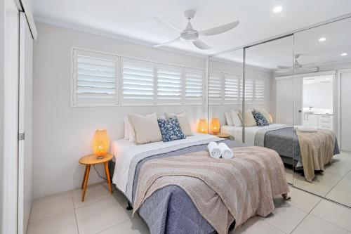 a bedroom with two beds and a ceiling fan at Chez Noosa Holiday Apartments in Sunshine Beach