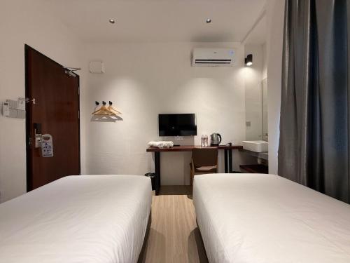 a hotel room with two beds and a desk with a computer at OYO 91193 Hi Inn Sibu Jaya in Sibu