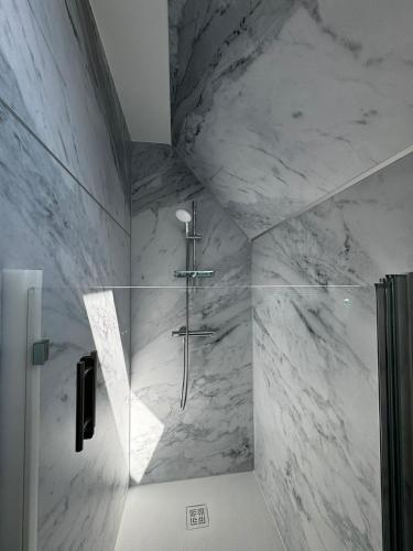 a bathroom with a shower with white marble walls at Au pré des pierres in Sancé