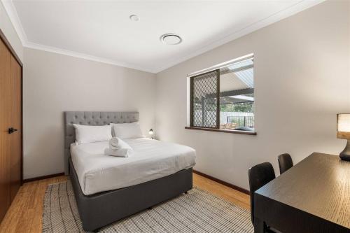Un dormitorio con una cama y una mesa y una ventana. en Prowse Beach House - Family Fun & Ocean Adventures, en Dunsborough