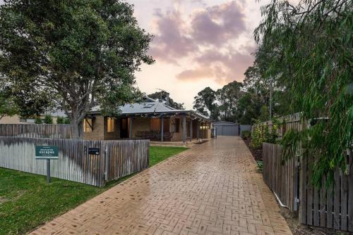 una casa con una valla y una entrada de ladrillo en Prowse Beach House - Family Fun & Ocean Adventures, en Dunsborough