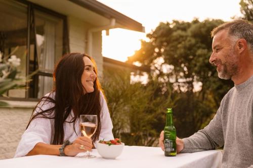 a man and woman sitting at a table with a glass of wine at Rotoroa Island Wildlife Sanctuary in Auckland