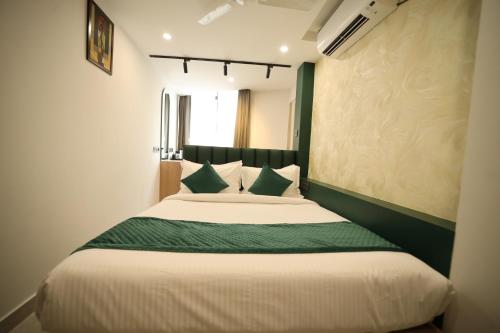 a bedroom with a large bed with a green headboard at Hotel Bilton Wilson Garden Near Nimhans Hospital in Bengaluru