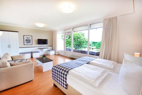 a hotel room with a large bed and a couch at Strandgrün Golf- & Spa Resort in Timmendorfer Strand