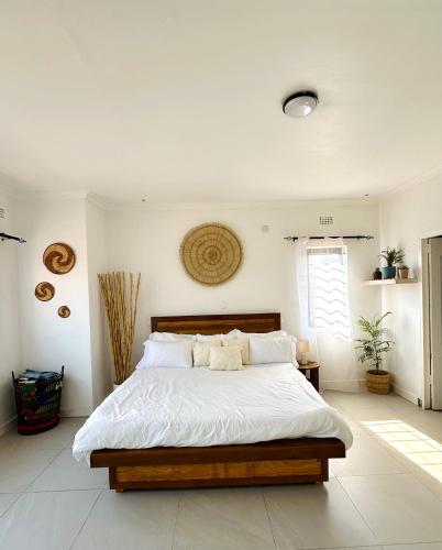 a bedroom with a large bed with white sheets at Qwithu Villa, Cozy Room in Shared 4-Bedroom House in Blantyre