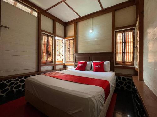 Un dormitorio con una cama grande con almohadas rojas. en OYO 93277 Villa Kemiloko Syariah, en Prigen