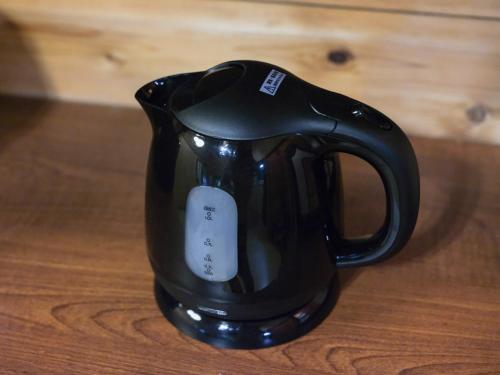 a black coffee cup sitting on a wooden table at mela villa in Tsumagoi