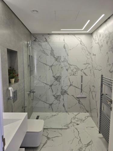 a marble bathroom with a shower and a toilet at Villa rooftop with stunning view apartment in Amman