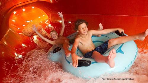 three people riding on a raft in a water slide at Haus Floresa in Lutzmannsburg