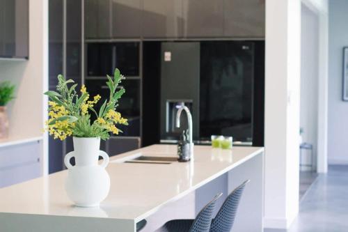 a kitchen with a white vase with flowers on a counter at Rainforest Retreat - Pool W Stunning Views in Bayview Heights