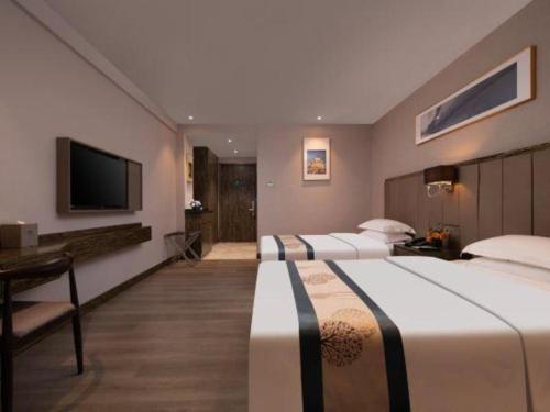 a hotel room with two beds and a flat screen tv at Landmark Hotel in Zhuhai